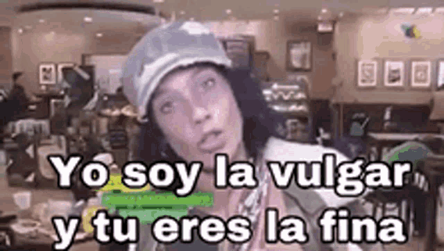 a man wearing a hat is making a funny face and says yo soy la vulgar y tu eres la fina .