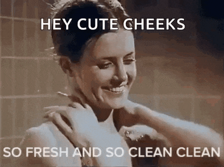 a woman is taking a shower with a towel around her shoulders and smiling .