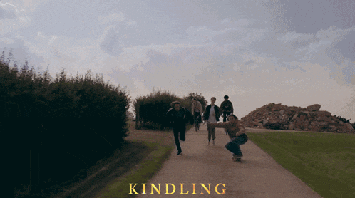 a group of people walking down a path with the word kindling in yellow