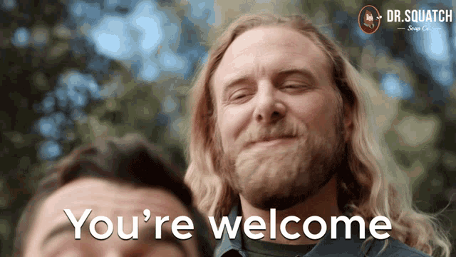 a man with a beard is smiling with the words you 're welcome behind him
