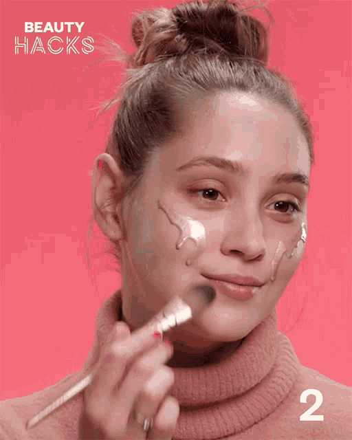 a woman is applying makeup and the number 2 is on the bottom right
