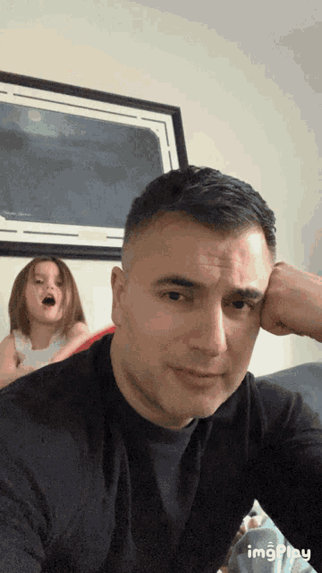 a man sitting on a couch with a little girl behind him and the words imgplay on the bottom right corner