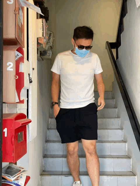 a man wearing sunglasses and a mask walking down stairs