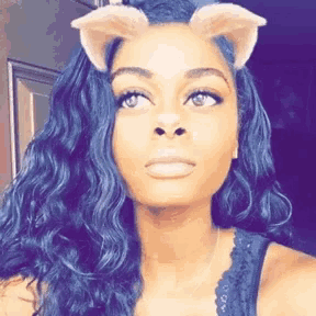a woman with long blue hair is wearing a cat ear filter .