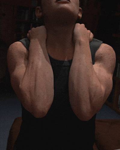 a man in a black tank top is holding his neck