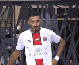 a man wearing a white shirt with the word mubadala on the front