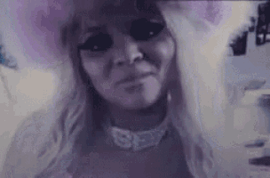 a close up of a woman 's face with black eyes and a choker necklace .