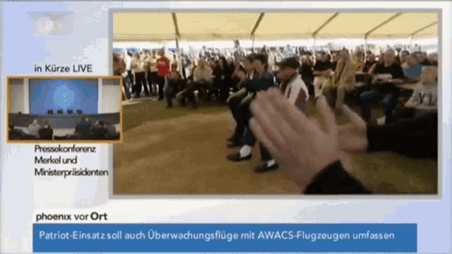 a screen shows a group of people applauding and says phoenix vor ort