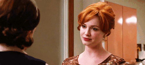a woman with red hair is standing next to another woman in a room .