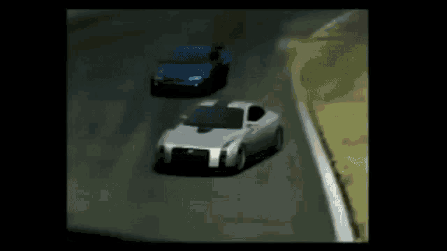 a blue car and a silver car are racing down a road