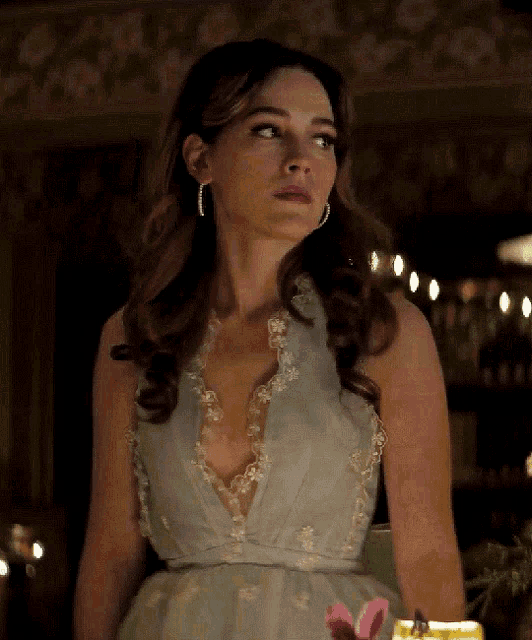 a woman in a light blue dress with a plunging neckline and earrings