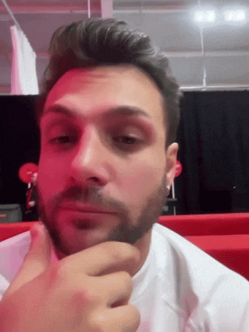 a man with a beard is making a face with his hand on his chin