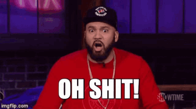 a man with a beard is wearing a red shirt and a black hat .