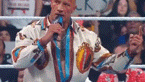 a man in a native american outfit is standing in a wrestling ring holding a microphone .