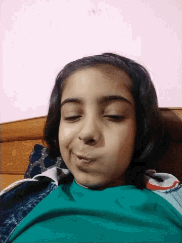 a young girl with her eyes closed and a green shirt on