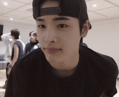 a young man wearing a black hat and a black shirt is looking at the camera