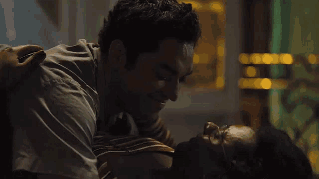 a man and woman are kissing in a dark room with a blurred background