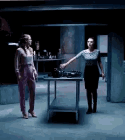 two women are standing in a dark room talking to each other