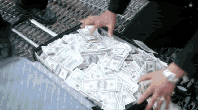 a suitcase filled with hundred dollar bills is being opened by a man wearing a watch