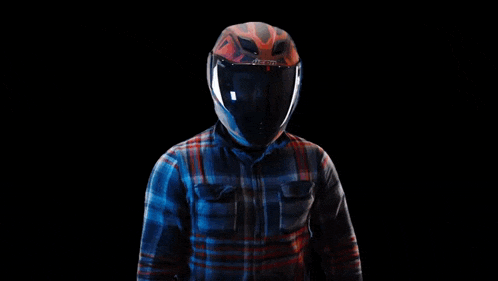 a man wearing a helmet and a plaid shirt is making a fist .
