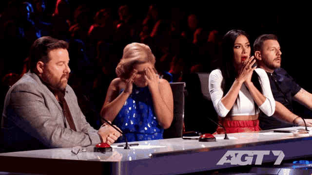 a group of people sitting at a table with a sign that says agt 7 on it