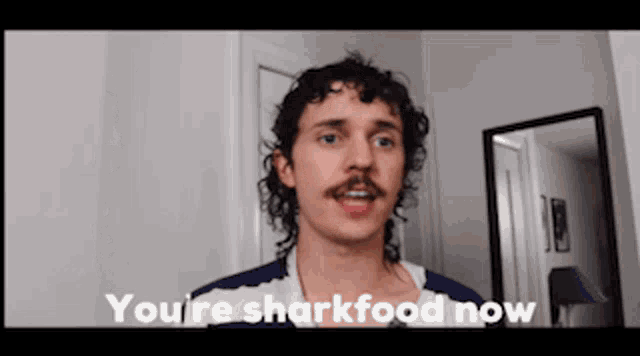 a man with a mustache says you 're sharkfood now in front of a mirror .