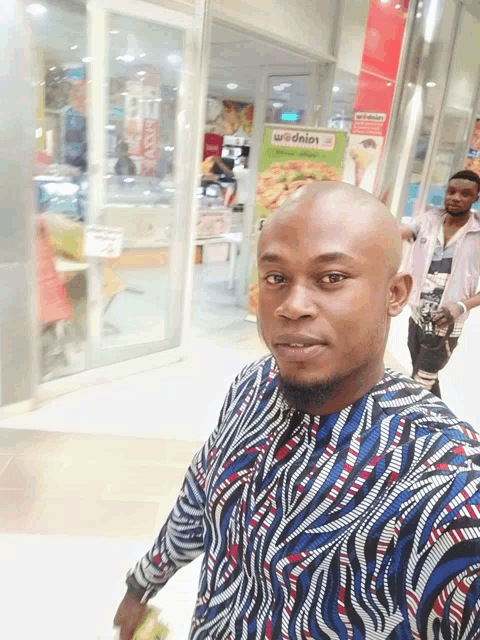 a man in a zebra print shirt is standing in front of a mcdonald 's advertisement