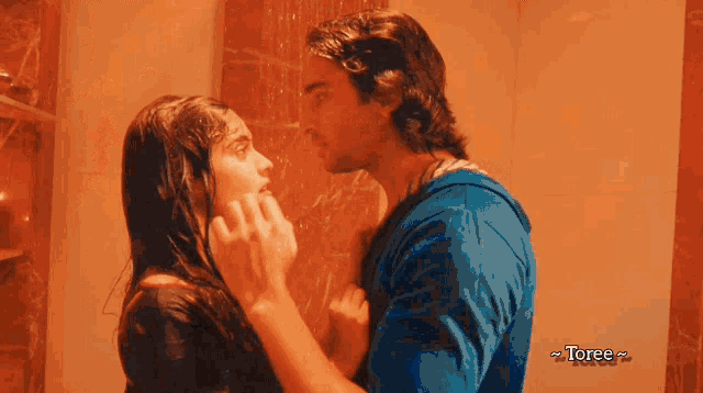 a man and a woman are kissing in a shower with toree written on the bottom right