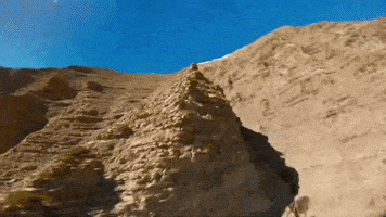 a sandy hillside with a blue sky behind it