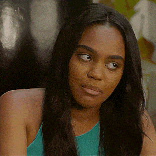 a woman in a blue tank top looks at the camera with a serious look on her face