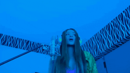 a woman singing into a microphone with the words cambiaste un ferrari por un twingo behind her