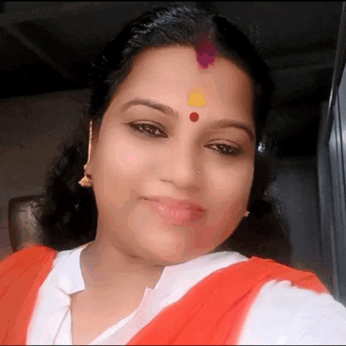 a woman with a red dot on her forehead looks at the camera