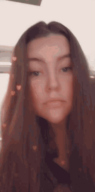 a woman with long brown hair is taking a selfie with hearts in her hair .
