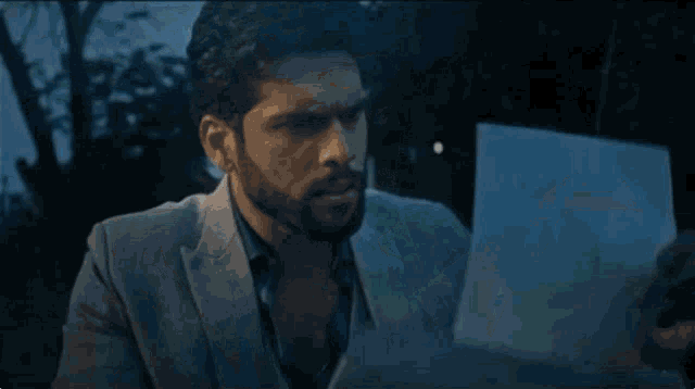 a man in a suit and tie is reading a piece of paper .