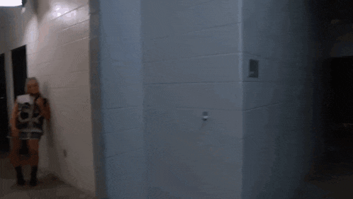 a woman is standing in a hallway with a white wall and a black door