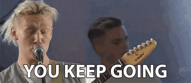 a man singing into a microphone with the words " you keep going " below him