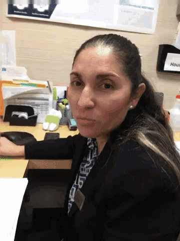 a woman sits at a desk with a sign that says house on it