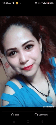 a woman in a blue shirt is taking a selfie on a phone