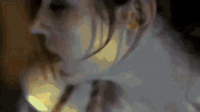 a close up of a woman 's face in a dark room with a candle .