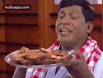 a man is holding a plate of food with his eyes closed .
