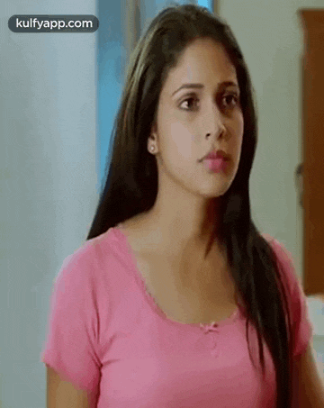 a woman in a pink shirt is standing in a room .