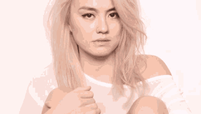 a woman with blonde hair is wearing a white off the shoulder shirt