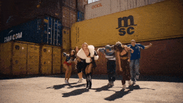 a group of people are dancing in front of a large yellow container that says msc