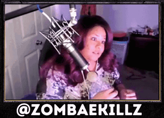 a woman with purple hair is sitting in front of a microphone with the words @zombaekillz below her
