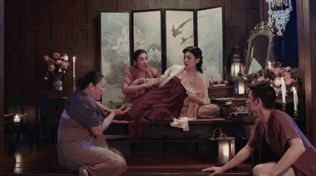 a group of people are sitting in a room with a painting on the wall behind them