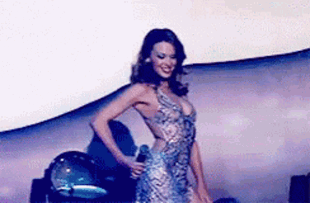 a woman is standing on a stage wearing a blue dress .
