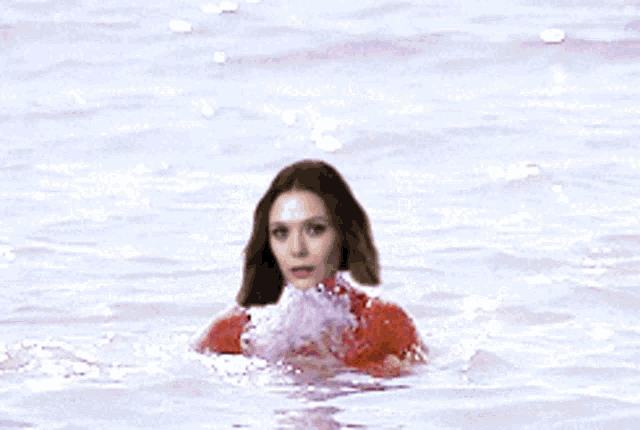 a woman in a red bikini is standing in the ocean