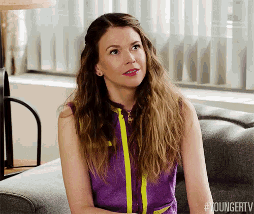 a woman is sitting on a couch with her arms crossed and looking up .