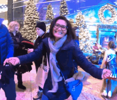 a woman wearing glasses is smiling in front of a christmas tree