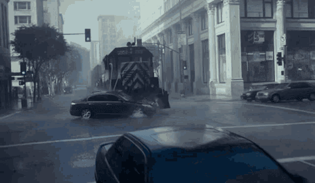 a red car is driving down a street in front of a train that says cargo on the side